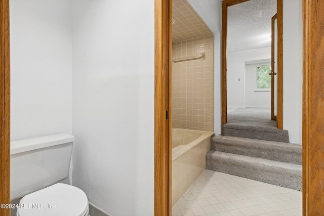 bathroom with a bath, a textured ceiling, and toilet