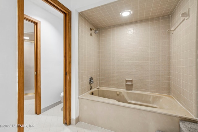 bathroom with tile patterned flooring, toilet, and tiled shower / bath