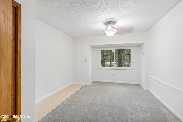 carpeted spare room featuring ceiling fan and a textured ceiling