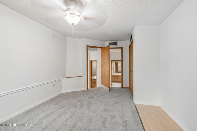 carpeted empty room with ceiling fan and a textured ceiling