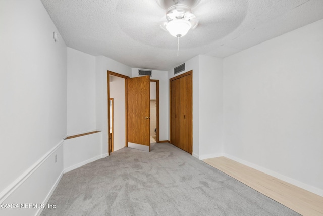 spare room featuring ceiling fan, light colored carpet, and a textured ceiling