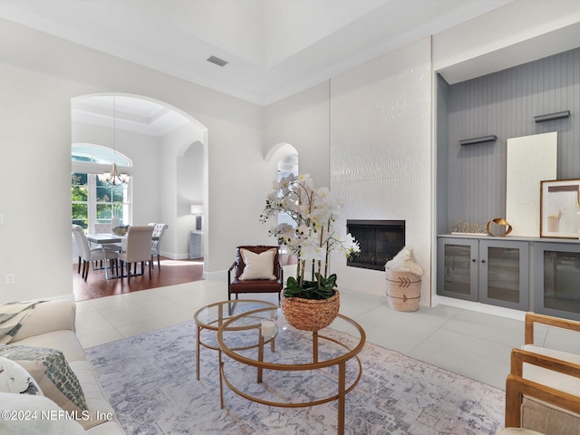 living room with a fireplace, light hardwood / wood-style flooring, a chandelier, and crown molding