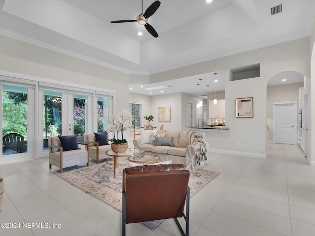 tiled living room featuring french doors, a towering ceiling, sink, ornamental molding, and ceiling fan