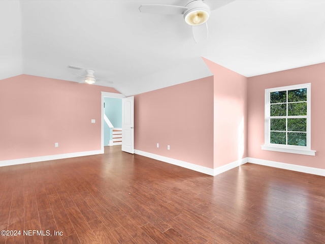 empty room with dark hardwood / wood-style flooring, lofted ceiling, and ceiling fan