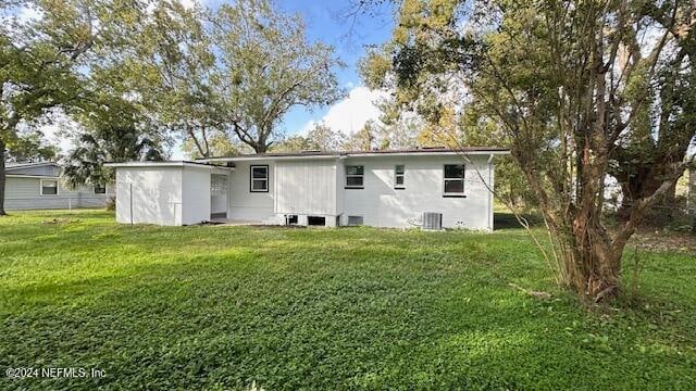 rear view of house featuring a lawn and central AC