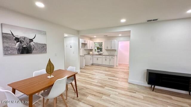 dining area with light wood-type flooring and a fireplace