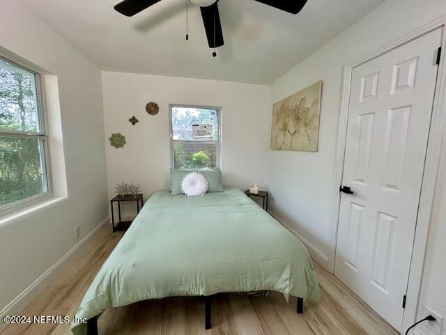 bedroom featuring ceiling fan, multiple windows, and light wood-type flooring