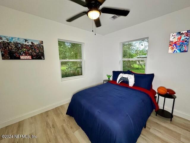 bedroom featuring ceiling fan, multiple windows, and light wood-type flooring