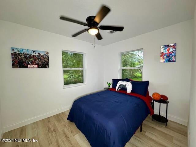 bedroom featuring multiple windows, ceiling fan, and light hardwood / wood-style flooring