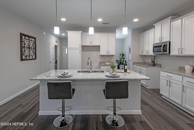 kitchen with white cabinetry, a center island with sink, and sink