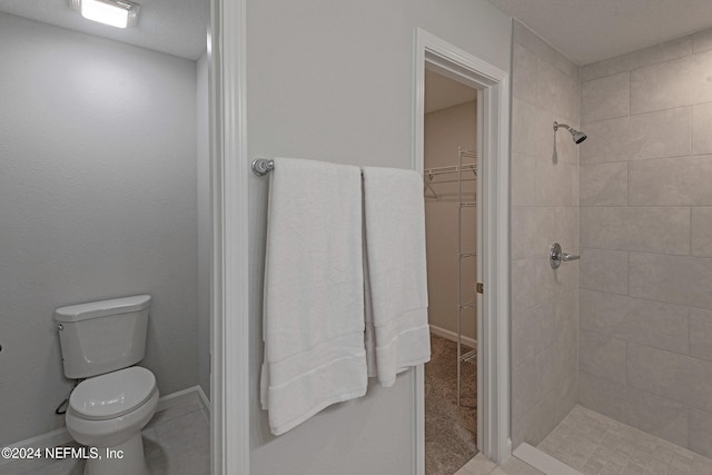 bathroom featuring tiled shower and toilet