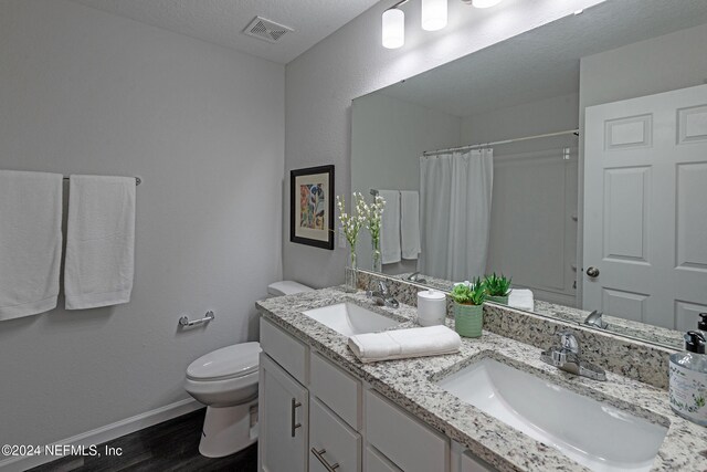 bathroom featuring toilet, a textured ceiling, hardwood / wood-style flooring, a shower with curtain, and vanity