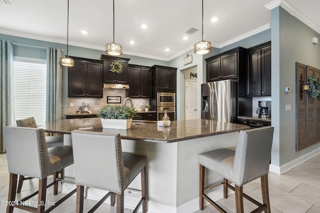 kitchen with decorative light fixtures, a center island with sink, and stainless steel appliances