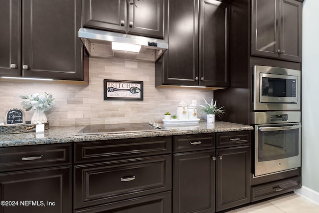 kitchen with stainless steel appliances, dark brown cabinetry, tasteful backsplash, light tile patterned flooring, and stone countertops