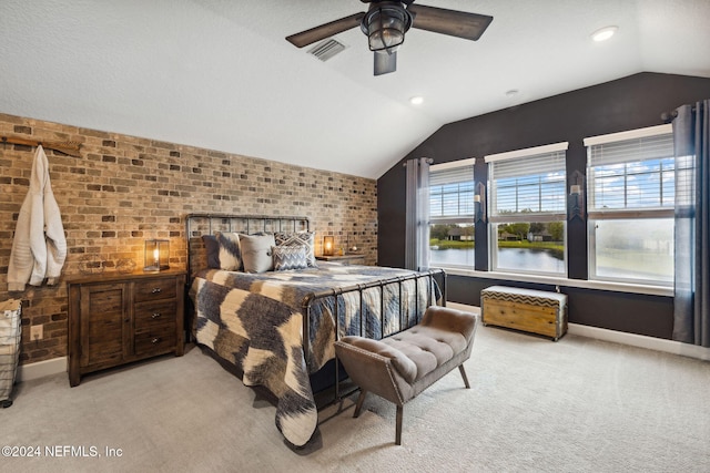 bedroom featuring vaulted ceiling, a water view, light colored carpet, ceiling fan, and brick wall