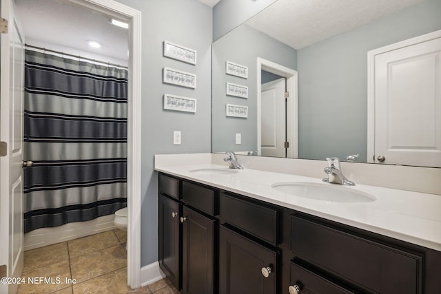 bathroom featuring vanity, tile patterned floors, a textured ceiling, and toilet