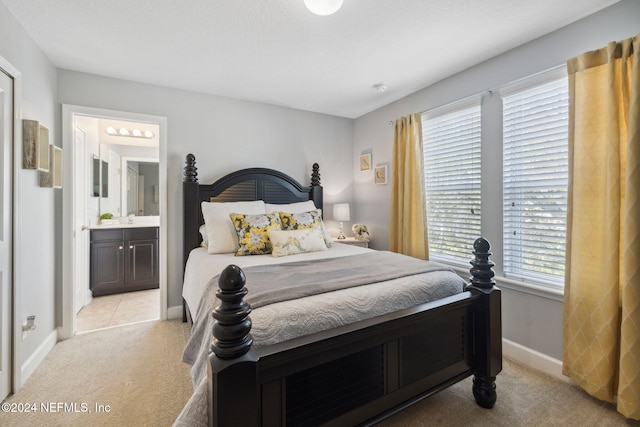 carpeted bedroom featuring ensuite bathroom and sink