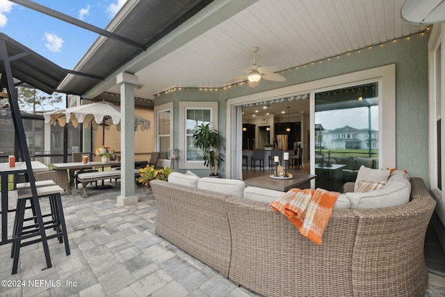 view of patio featuring glass enclosure, an outdoor hangout area, and ceiling fan