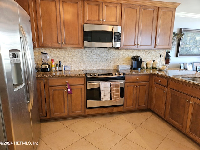 kitchen with appliances with stainless steel finishes, light tile patterned flooring, crown molding, and stone countertops