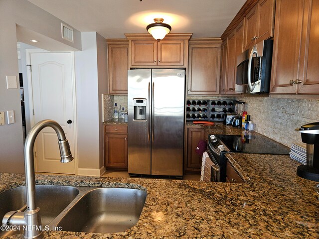 kitchen featuring appliances with stainless steel finishes, sink, and dark stone countertops