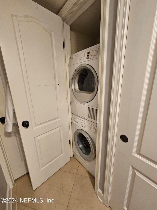 clothes washing area featuring light tile patterned flooring and stacked washer / drying machine