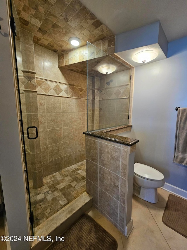 bathroom with toilet, tile patterned flooring, and a shower with shower door