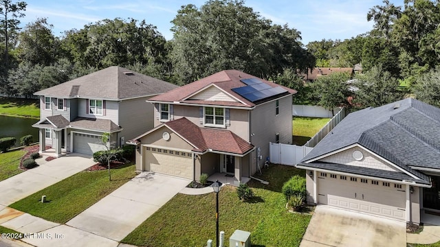 view of front of home with a garage, a front yard, and solar panels