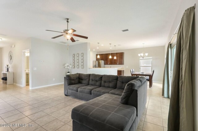 tiled living room with ceiling fan with notable chandelier