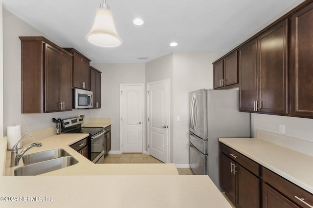 kitchen featuring appliances with stainless steel finishes, decorative light fixtures, dark brown cabinetry, light tile patterned floors, and sink