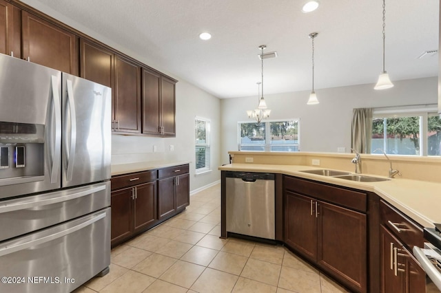 kitchen featuring stainless steel appliances, dark brown cabinetry, sink, light tile patterned floors, and pendant lighting