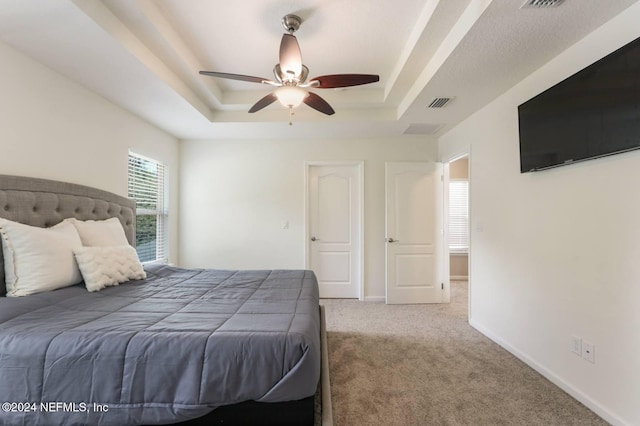 bedroom with a tray ceiling, carpet flooring, and ceiling fan