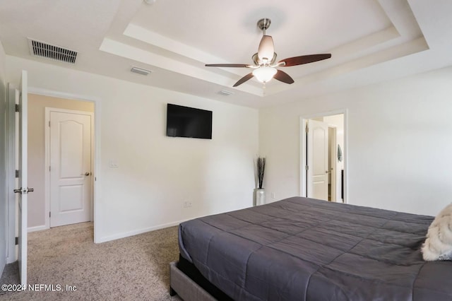 bedroom with ceiling fan, carpet flooring, and a raised ceiling