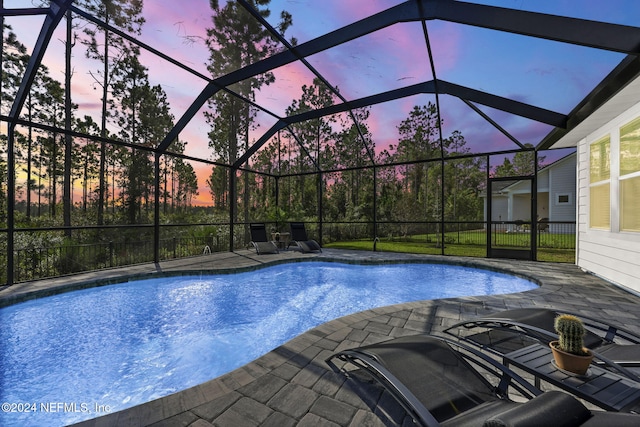 pool at dusk featuring a patio and a lanai