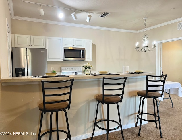 kitchen featuring light carpet, track lighting, stainless steel appliances, an inviting chandelier, and white cabinets