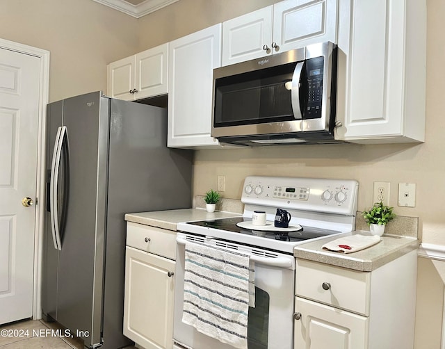 kitchen featuring white cabinetry, light tile patterned floors, stainless steel appliances, and ornamental molding