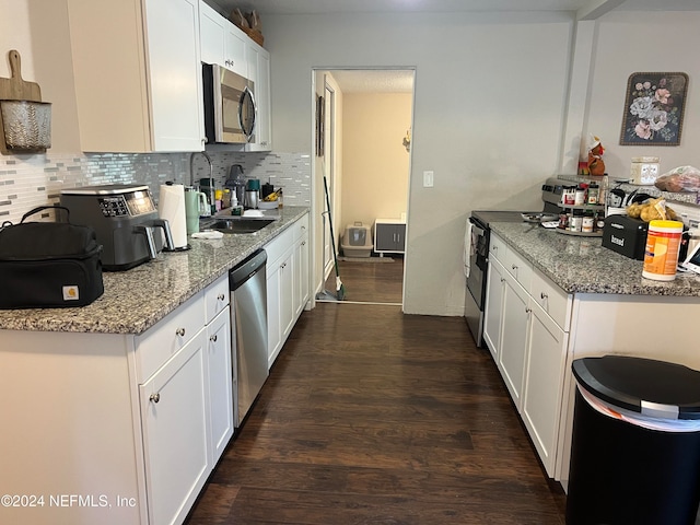 kitchen with white cabinetry, sink, light stone countertops, dark hardwood / wood-style floors, and appliances with stainless steel finishes