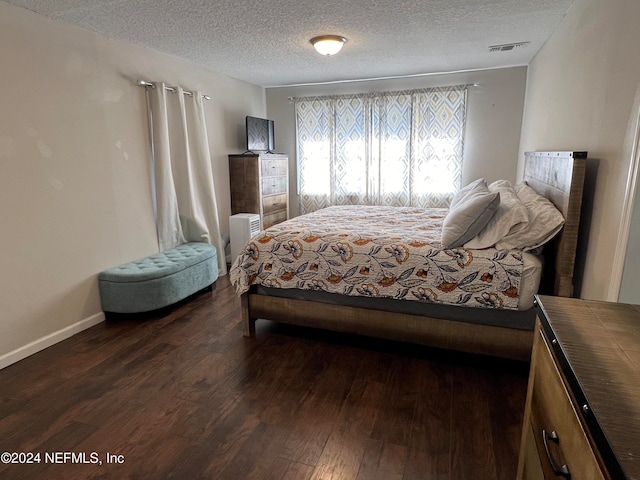 bedroom featuring dark hardwood / wood-style flooring and a textured ceiling