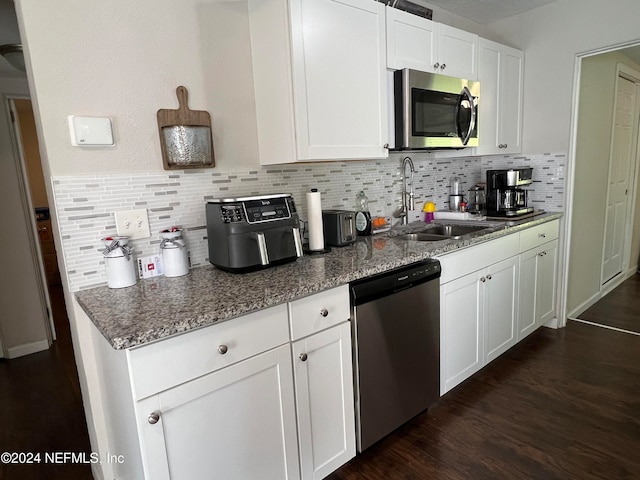 kitchen with white cabinetry, sink, stainless steel appliances, dark hardwood / wood-style flooring, and dark stone counters