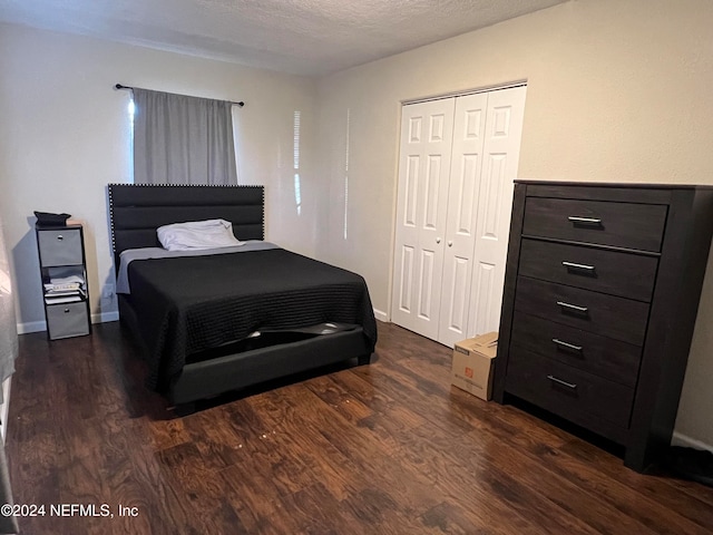 bedroom with a closet, dark wood-type flooring, and a textured ceiling