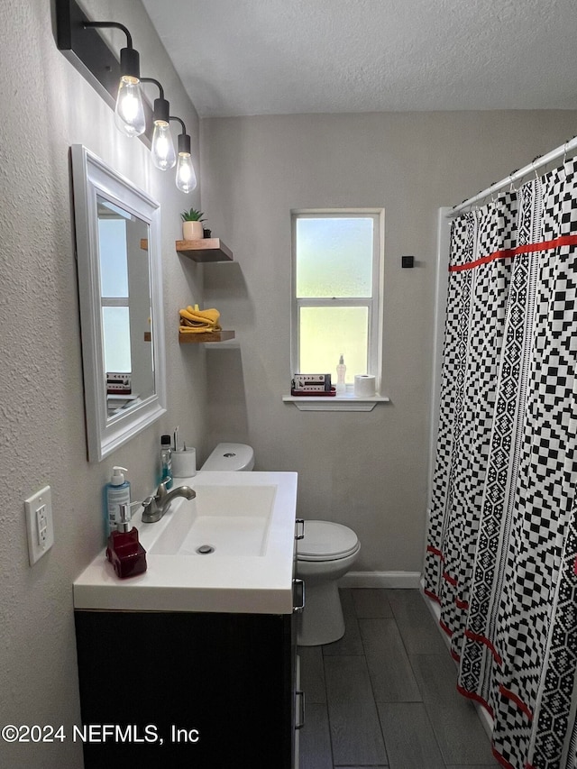 bathroom with a shower with shower curtain, vanity, toilet, and a textured ceiling