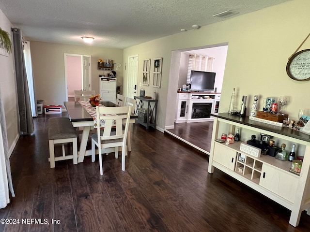 dining space with dark wood-type flooring and a textured ceiling