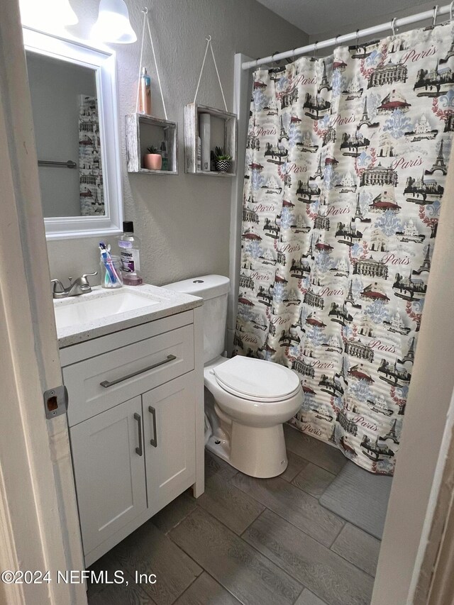 bathroom featuring curtained shower, hardwood / wood-style floors, vanity, and toilet