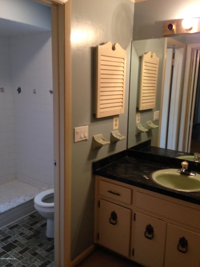 bathroom featuring tile patterned floors, vanity, toilet, and tiled shower