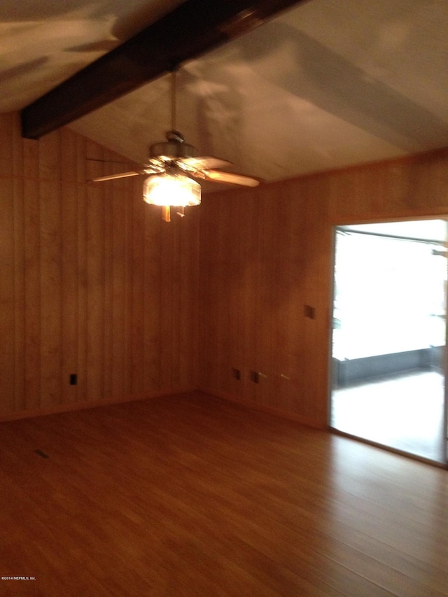 spare room with wood walls, hardwood / wood-style floors, and vaulted ceiling with beams