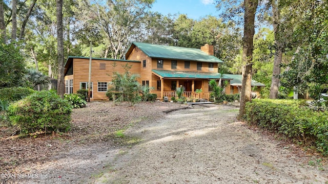 7816 Whispering Pines Ln, Glen St Mary, FL 32040 - chalet / cabin with covered porch, a chimney, driveway, metal roof, and view of scattered trees