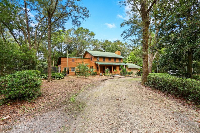 7816 Whispering Pines Ln, Glen St Mary, FL 32040 - view of front of property featuring driveway, a chimney, covered porch, and view of scattered trees
