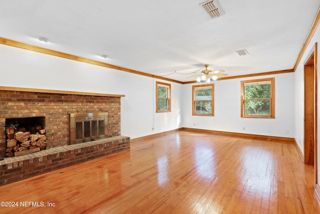 unfurnished living room featuring a brick fireplace, ceiling fan, light wood-type flooring, and ornamental molding