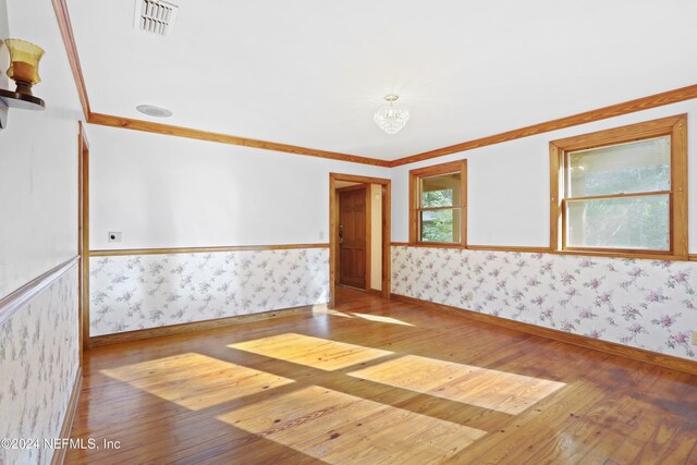 7816 Whispering Pines Ln, Glen St Mary, FL 32040 - spare room featuring wallpapered walls, wood-type flooring, baseboards, a wainscoted wall, and ornamental molding