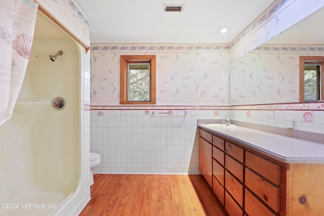 bathroom featuring tile walls, wood-type flooring, and a healthy amount of sunlight