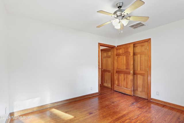 unfurnished bedroom with hardwood / wood-style floors, ceiling fan, and a closet